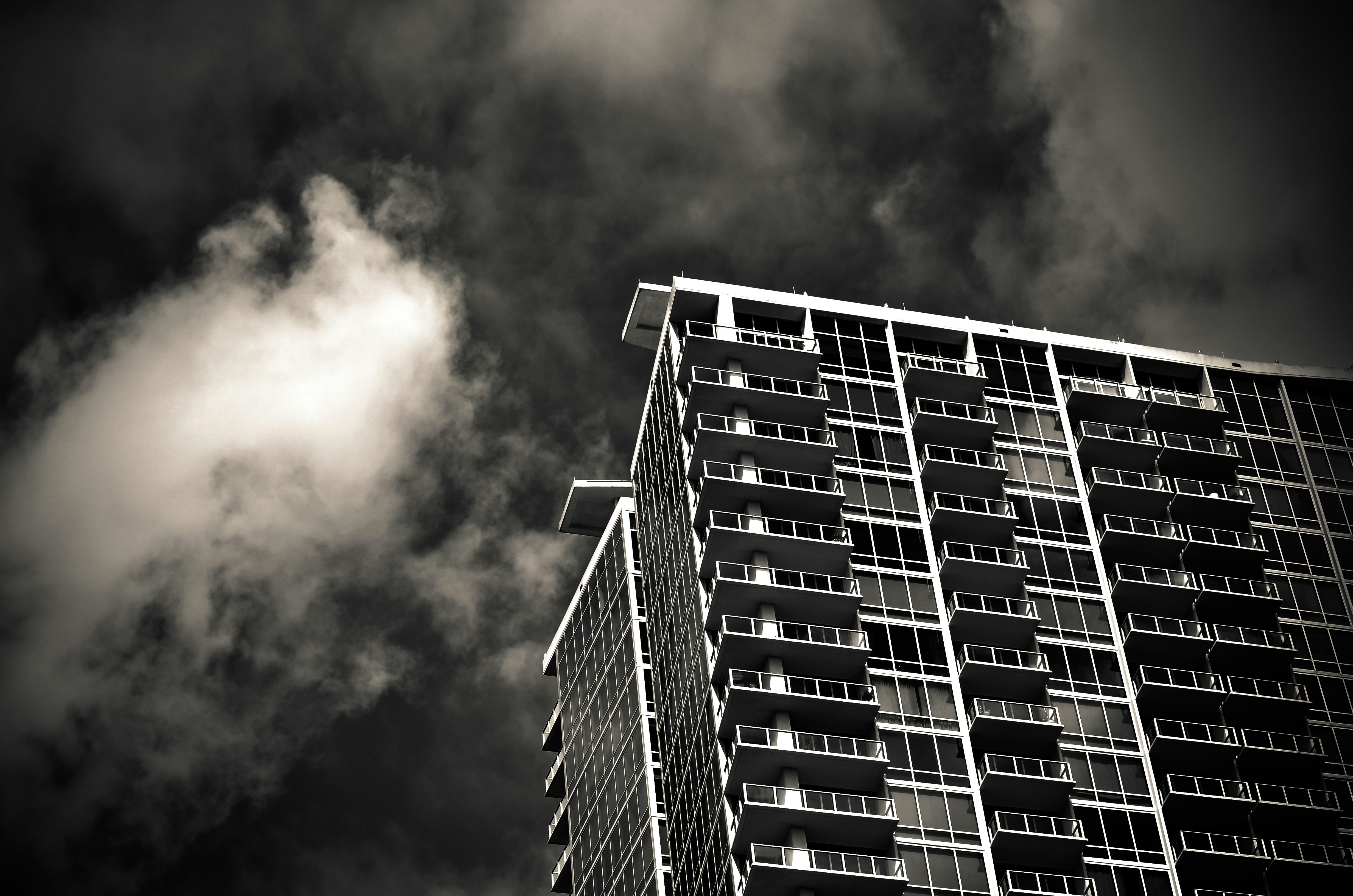 grayscale photography of building under cloudy sky